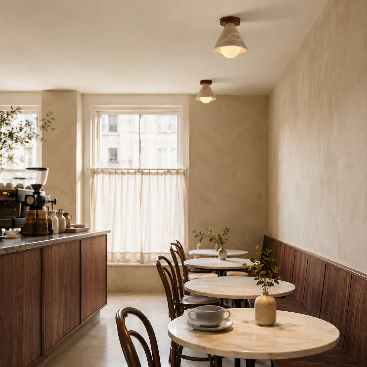Travertine cone ceiling light over the counter of a warm minimalist cafe