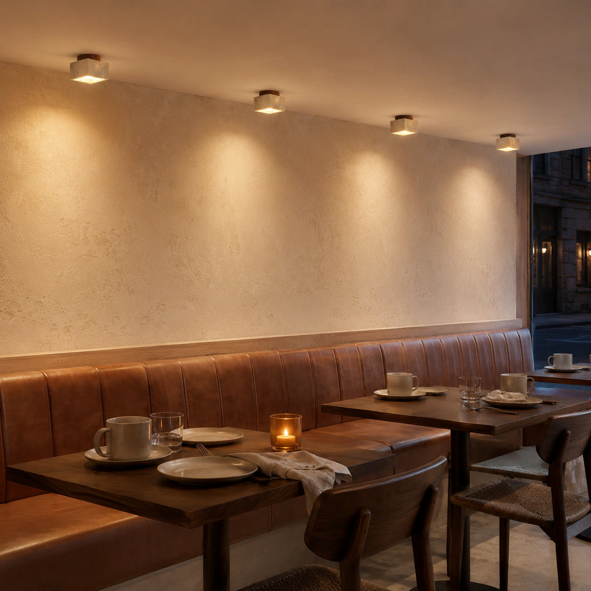 Travertine cube ceiling light above leather banquette seating in a restaurant