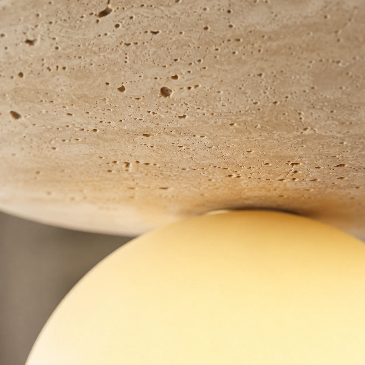 Close-up of the travertine grain on the beige disc ceiling light