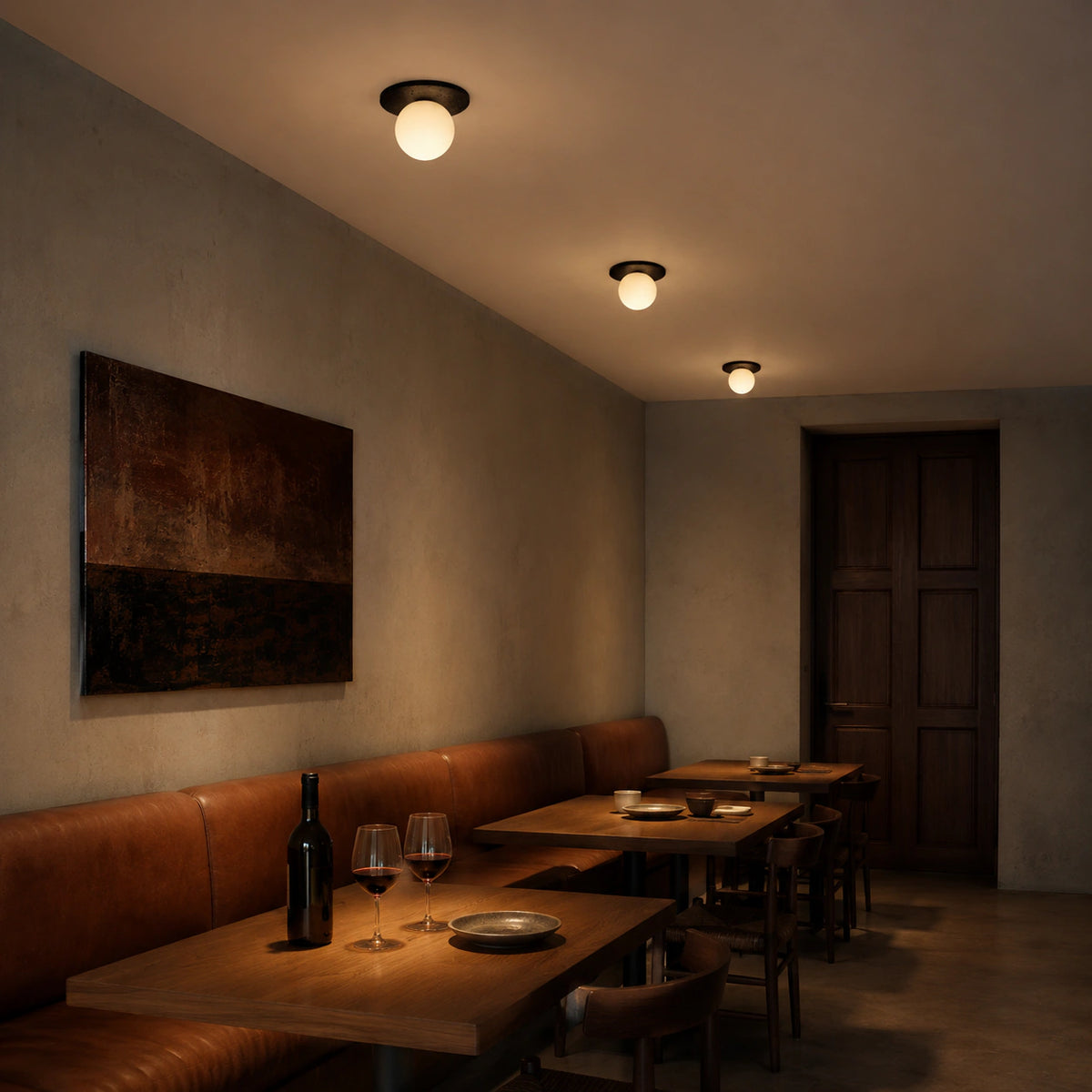 Black travertine disc ceiling light above leather banquette seating in a restaurant