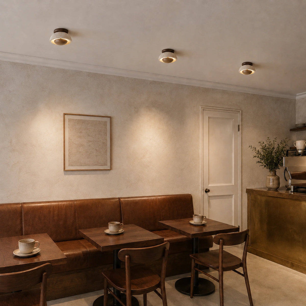 Travertine ceiling light with a wood reflector over the counter of a warm minimalist cafe