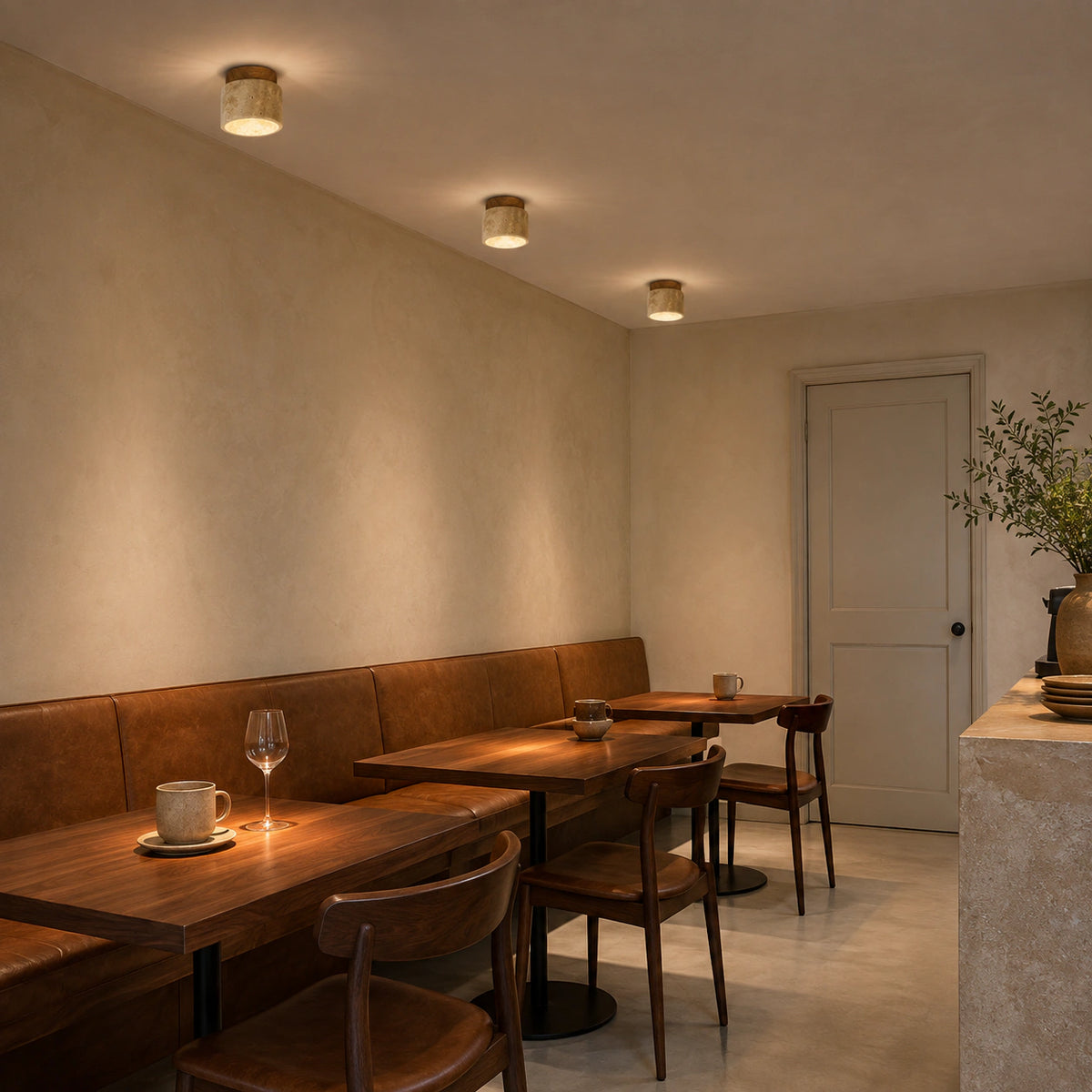 Travertine drum ceiling light over the counter of a warm minimalist cafe