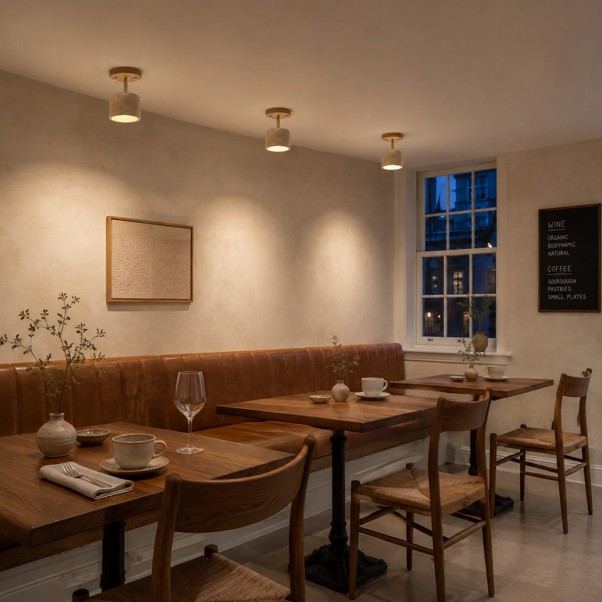 Adjustable travertine drum spotlight above leather banquette seating in a restaurant