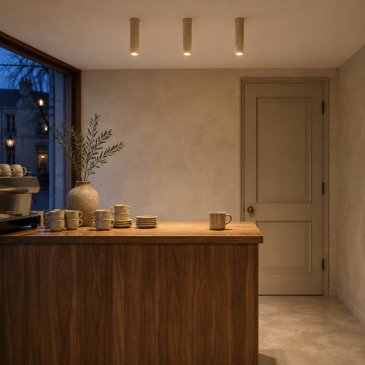 Slim travertine tube downlight fitted to the ceiling of a warm oak kitchen