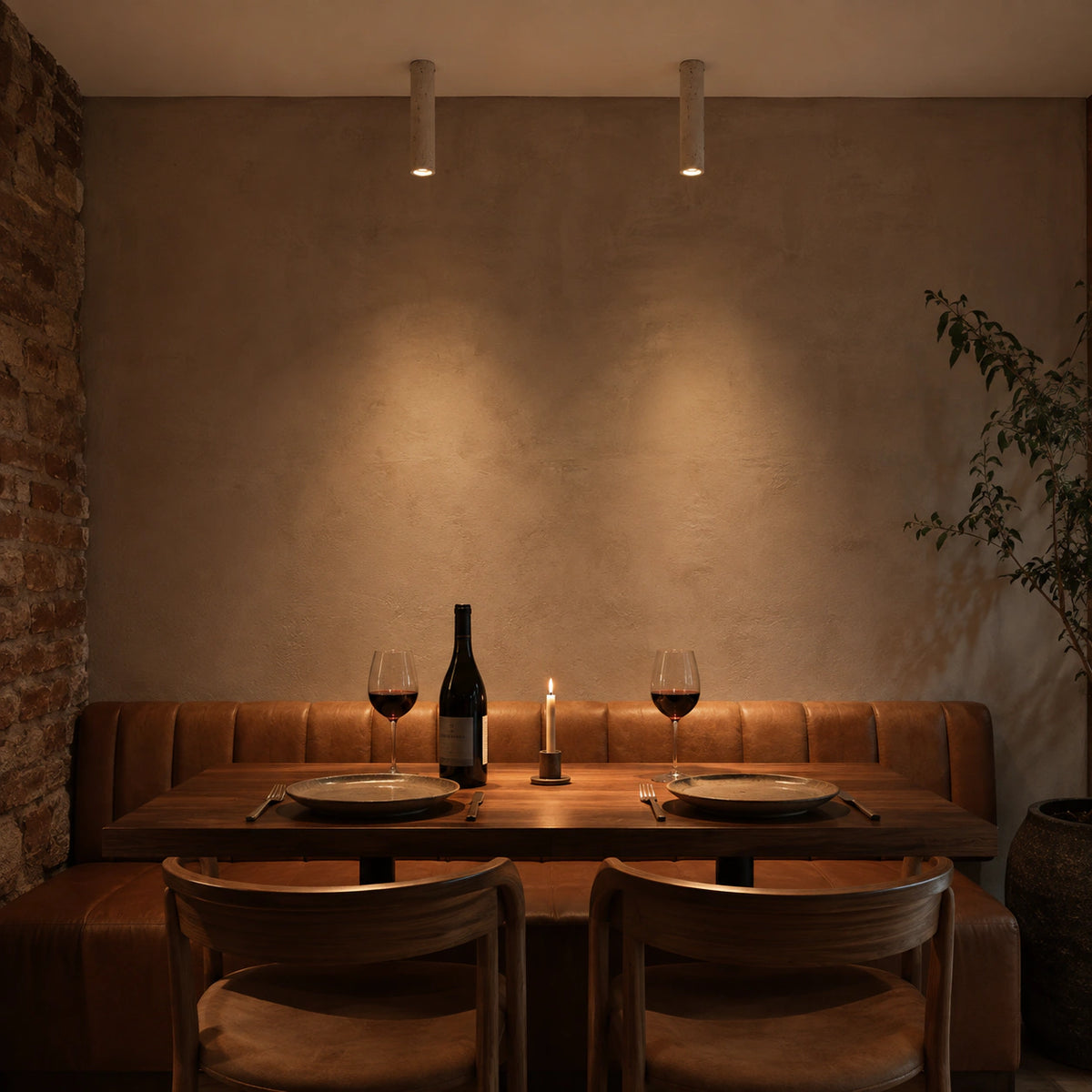 Slim travertine tube downlight above leather banquette seating in a restaurant