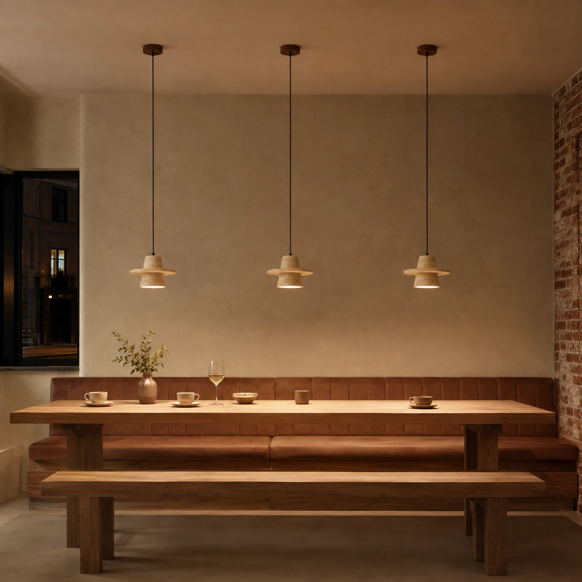 Travertine cone pendant above banquette seating in a restaurant