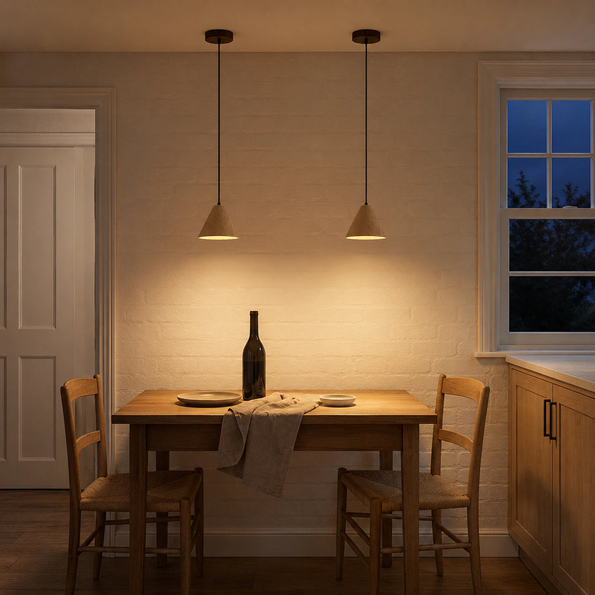 Skye cone pendant in beige travertine above a dining table in a minimalist dining room