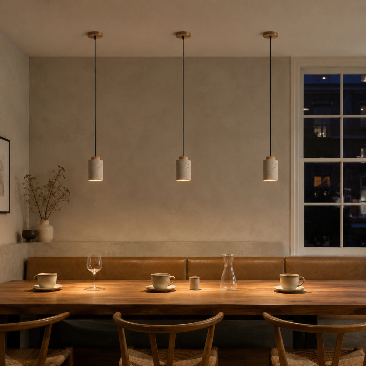 Fairlie travertine cylinder pendant in oak above a restaurant table with banquette seating