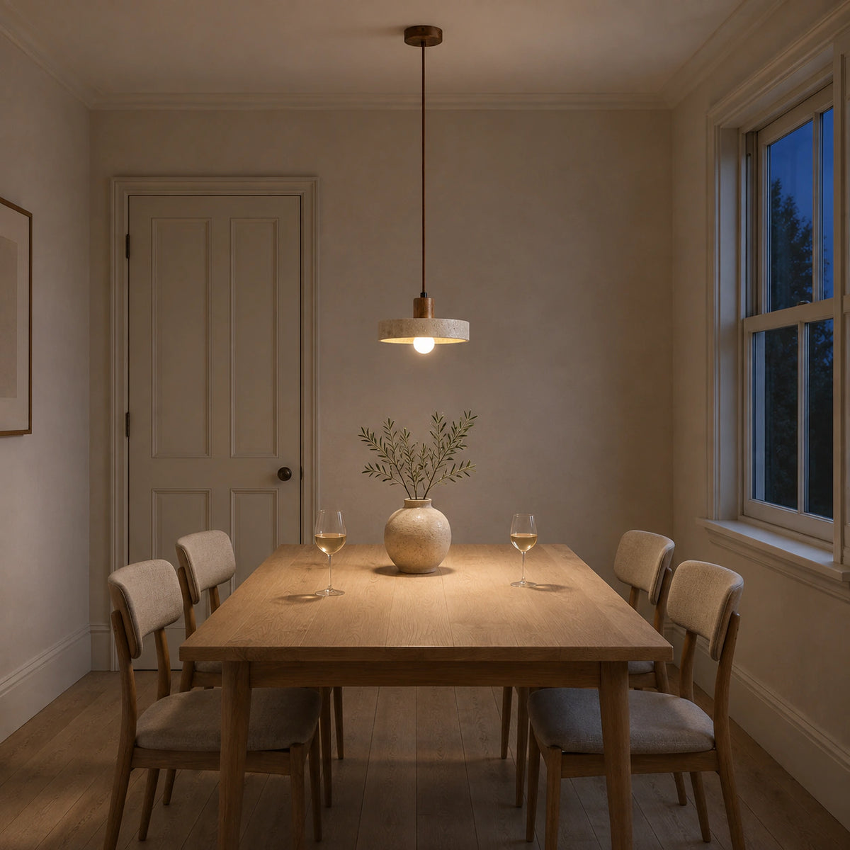 Salcombe travertine disc pendant in walnut above a dining table in a minimalist dining room