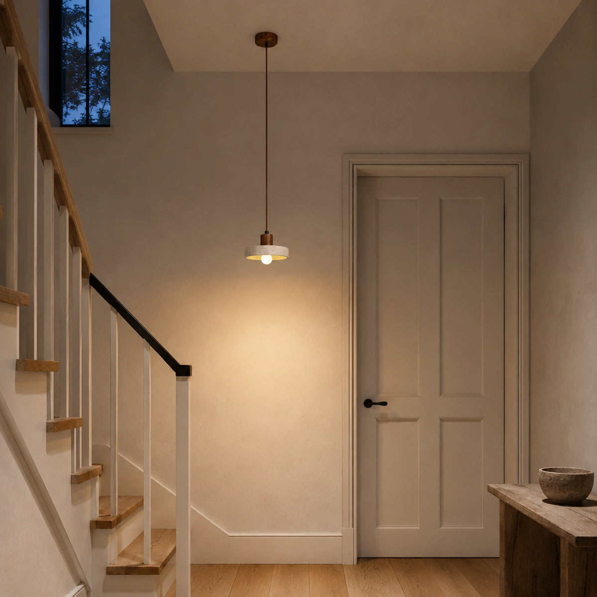 Salcombe travertine disc pendant in walnut hanging above a staircase landing