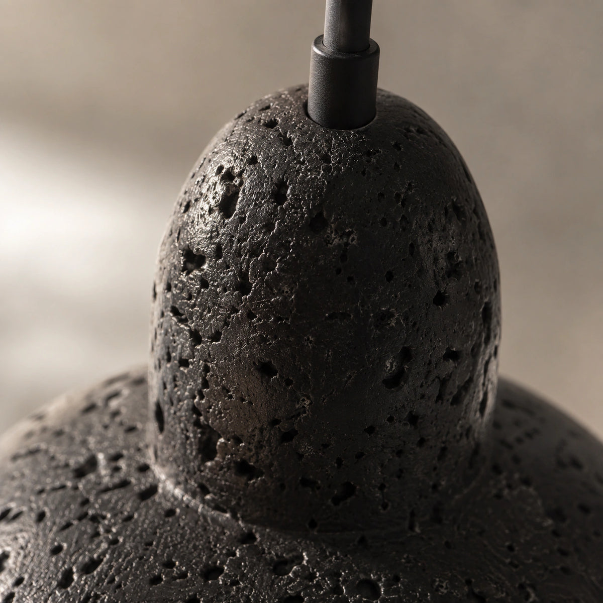 Close-up of the natural pitting on the black travertine of the Blackmoor dome pendant