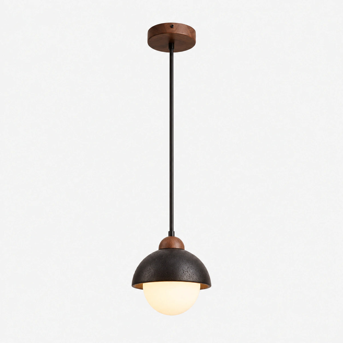 Black travertine half dome pendant light capping an opal glass globe on a white background