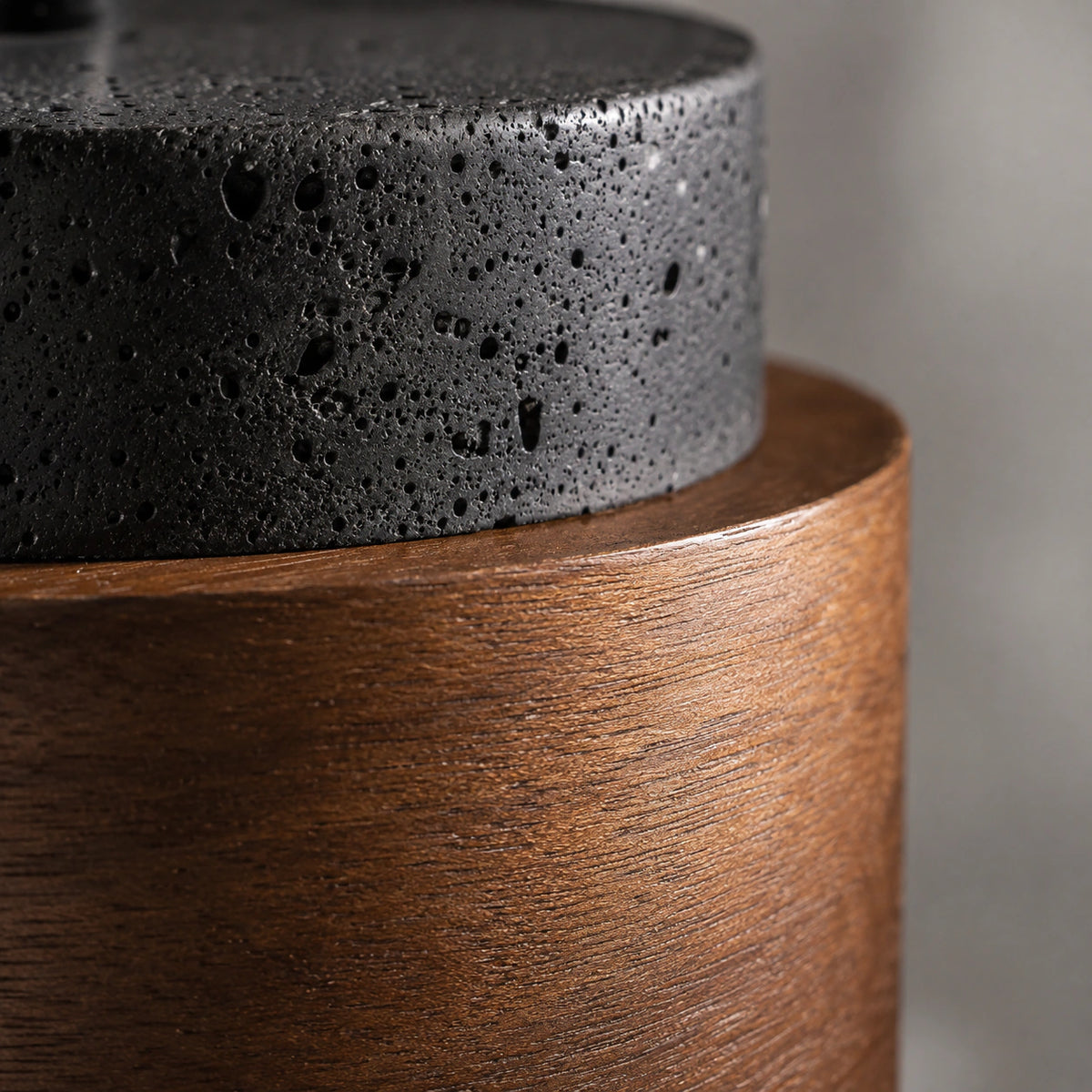 Close-up of the pores in the black travertine against the wood band on the Barrow pendant