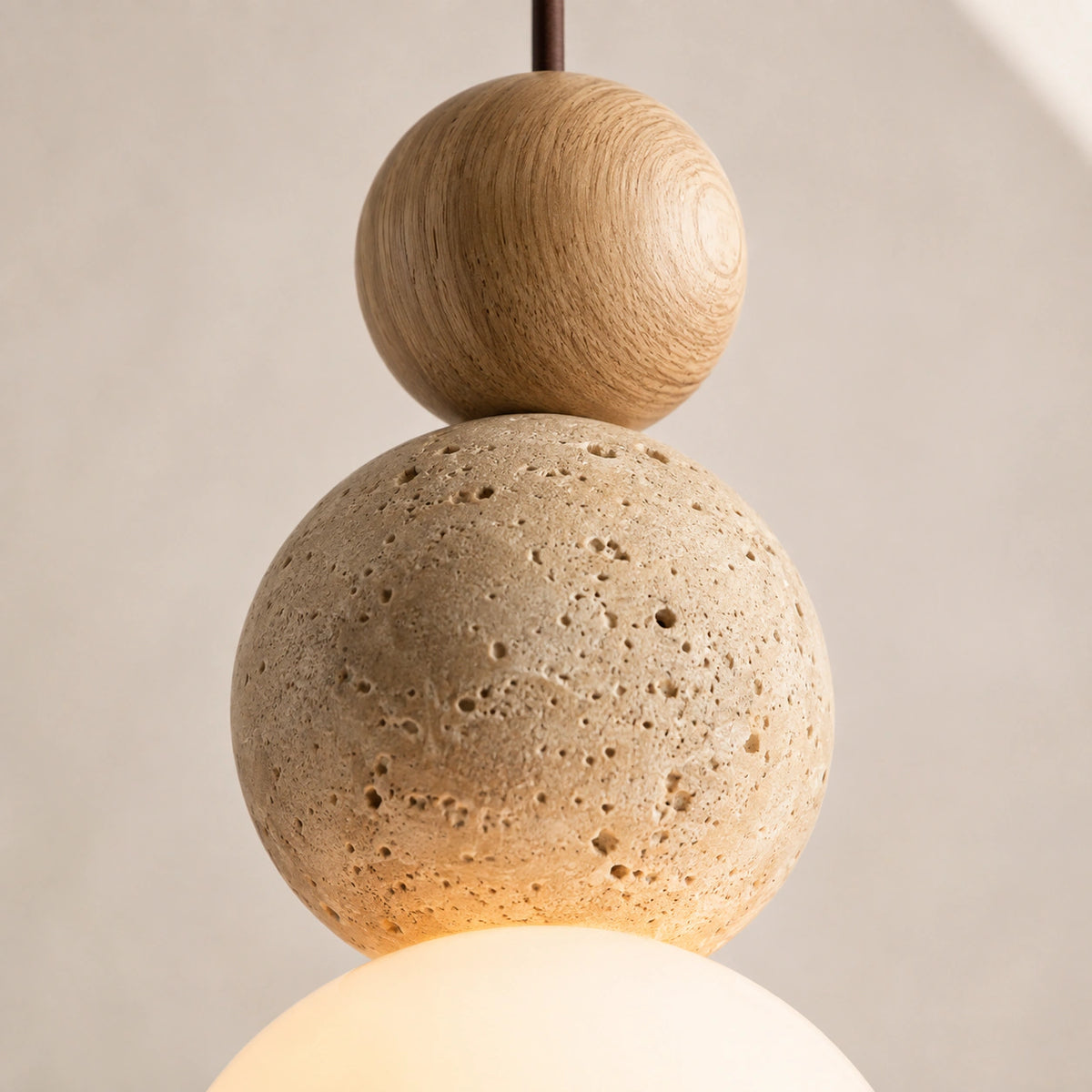 Close-up of the open pores on the travertine sphere above the opal globe, with an oak ball
