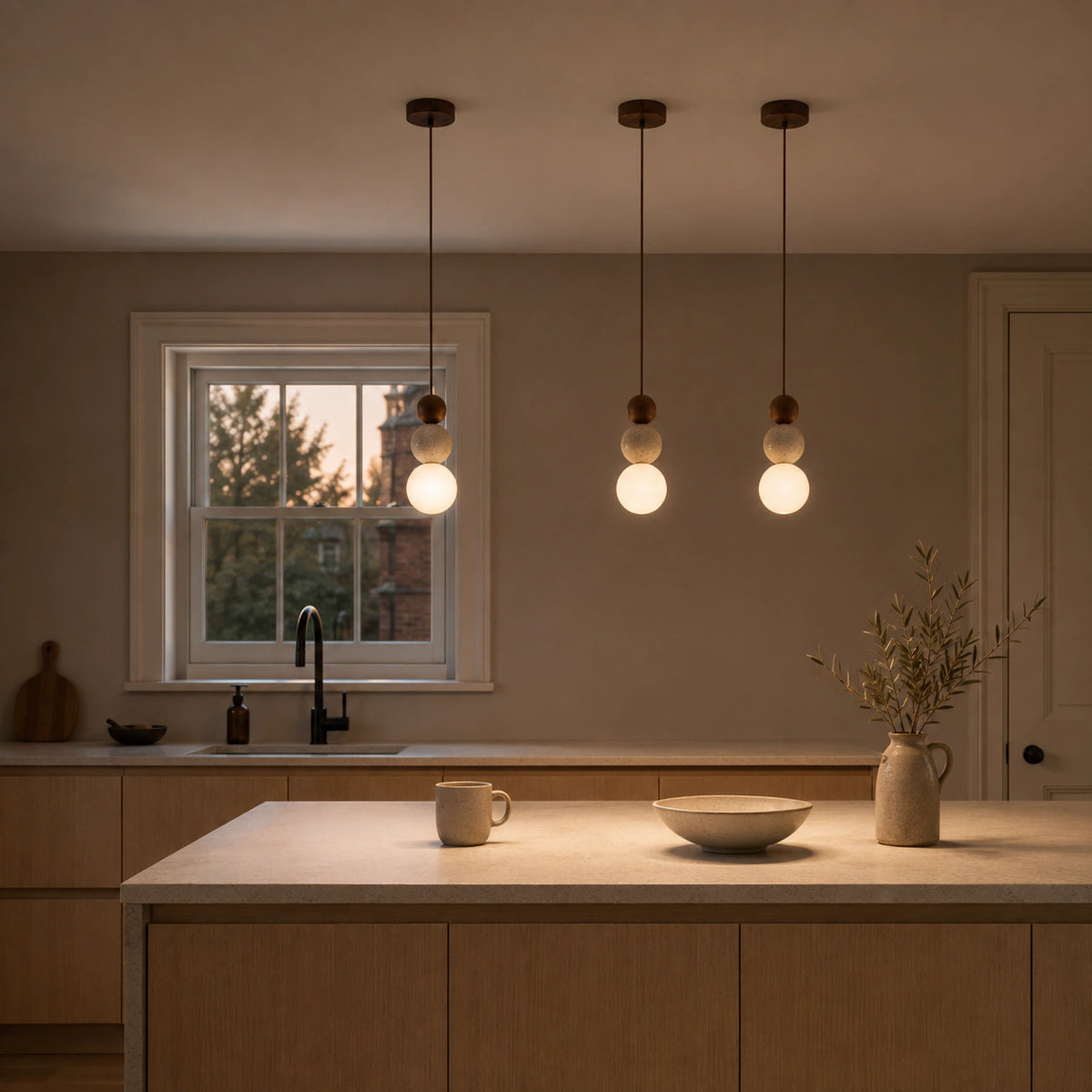 Sudbury travertine sphere pendant in walnut hanging above a kitchen island