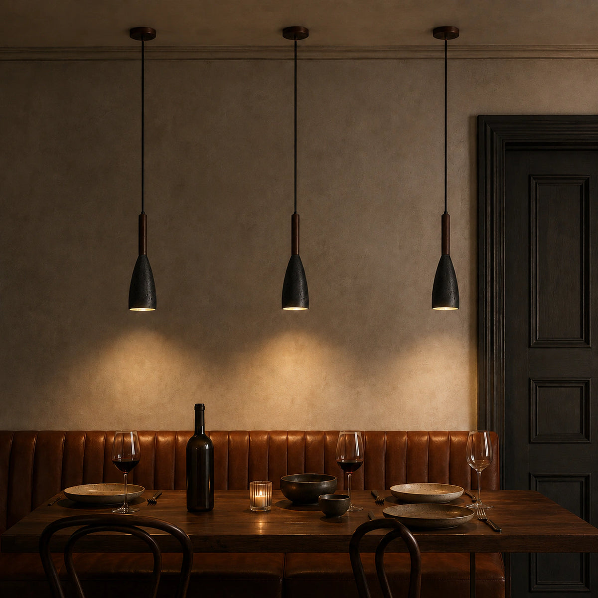Coalbrook tall black travertine pendant above a restaurant table with banquette seating