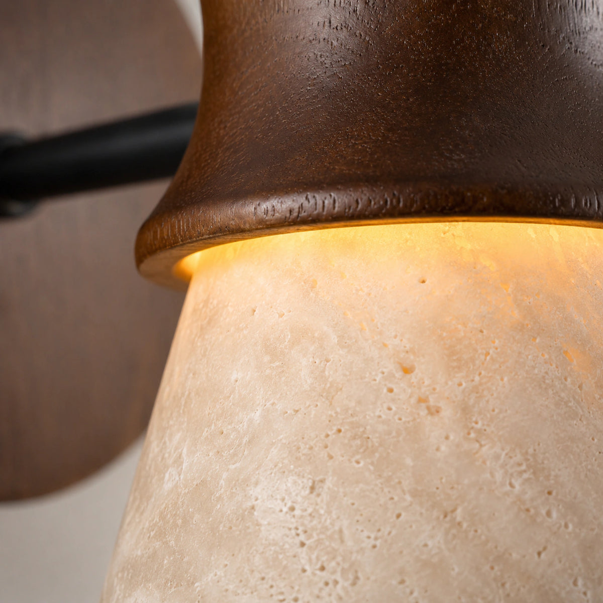 Close-up of the turned walnut collar meeting the travertine cone on the Ashwell wall light