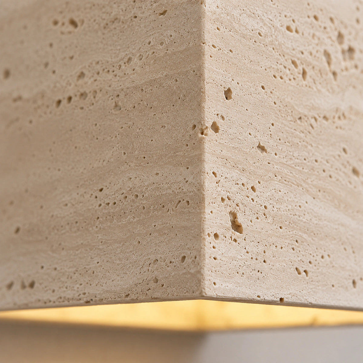 Close-up of the open pores in the solid travertine on the Melbury cube wall light