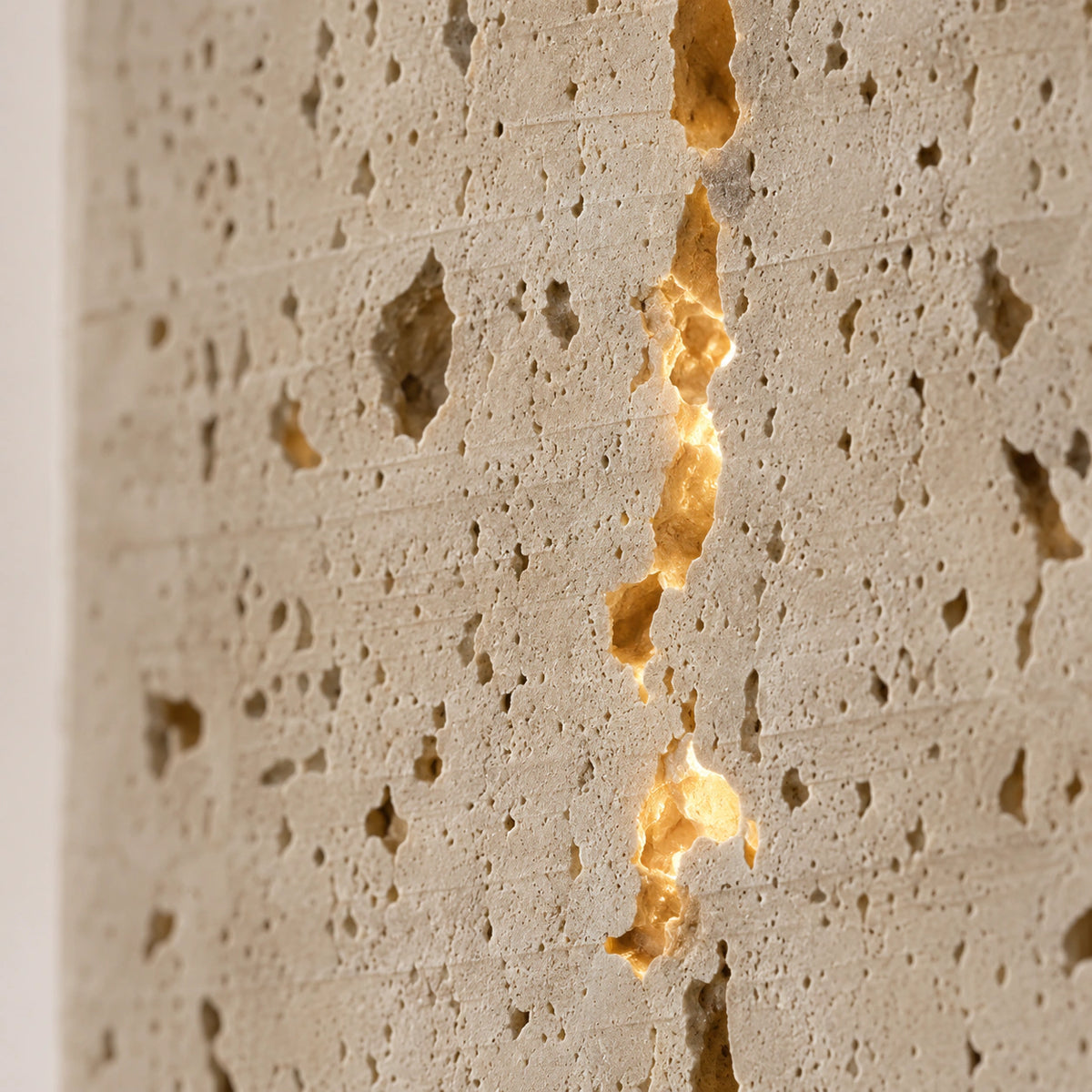 Close-up of light passing through the seams and pores of the Newlyn travertine wall light