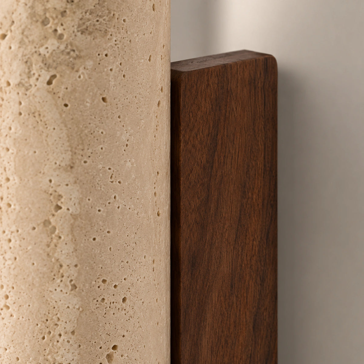 Close-up of the travertine grain and walnut backplate on the Farndon wall light